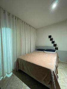 Cama en habitación con cortinas blancas en Apartamento 04 - Dois quartos e cozinha, en Balneário Camboriú