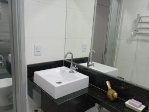 a bathroom with a white sink and a mirror at Apto 201 Familiar no centro do NB in Núcleo Bandeirante +5 photos