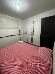 a bedroom with a bed with a red checkered blanket at Apartamento 05 - Um quarto, sala e cozinha in Balneário Camboriú