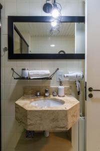 ein Badezimmer mit einem Steinwaschbecken und einem Spiegel in der Unterkunft Rosa Edificio Morada das Hortêsias in Gramado + 14 Fotos