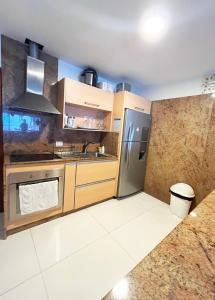 une cuisine avec des armoires en bois et un réfrigérateur en acier inoxydable dans l'établissement Sunrise vista al mar!, à San Andrés