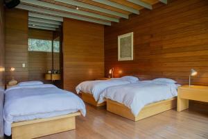 帕查卡马克Elegant 5BR with Garden view Home in Cieneguilla的一间木墙房间里有两张床