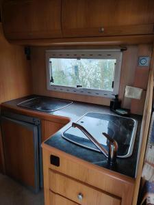 eine Küche mit einem Waschbecken und einem Fenster in einem Wohnwagen in der Unterkunft Séjour insolite Camping-car fixe in Marennes