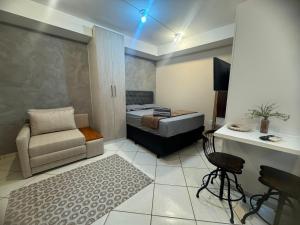 a small room with a bed and a couch and a chair at Casamar Lofts, Praia dos Anjos Arraial do Cabo in Arraial do Cabo