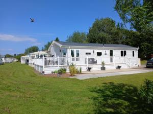 a white house with a porch and a yard at Sea Breeze, Vintage 90, Luxury 2 bed Lodge, Skegness, 2 friendly - East Coast Holidays in Winthorpe