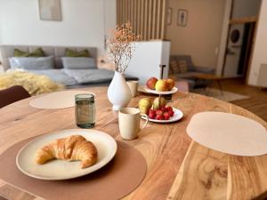 a wooden table with plates of bread and fruit on it at Pretti Apartments - Neu, Stilvoll, Zentral, Komfortabel, Geräumig & Ruhig in Bamberg