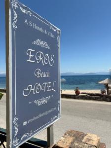 a sign for a beach hotel next to the ocean at Eros Beach Hotel in Benitses