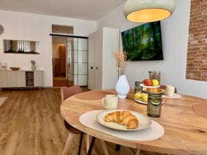 a table with a plate of croissants and fruit on it at Pretti Apartments - Neu, Stilvoll, Zentral, Komfortabel, Geräumig & Ruhig in Bamberg