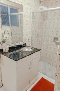 a white bathroom with a sink and a mirror at Apartamento amplo in Pelotas