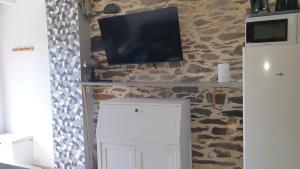 a television on a stone wall with a white cabinet at l'antre de Merlin in Tréhorenteuc