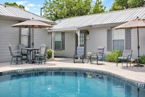 a swimming pool with chairs and a table and umbrella at Main Street Retreat #2 - King Bed, On Main St, Shared Hot Tub & Pool in Fredericksburg