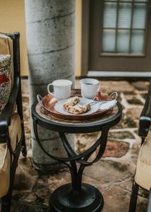 a table with a plate of food and two cups on it at Main Street Retreat #2 - King Bed, On Main St, Shared Hot Tub & Pool in Fredericksburg