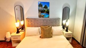 a bedroom with a bed with two lamps and two mirrors at HOPE-always in Cape Town