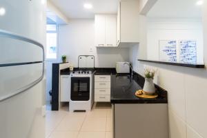 イタパリカにあるConforto + Vista Mar • 2 Quartos Casal • NOMDSのキッチン(白い家電製品、黒いカウンタートップ付)