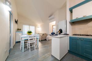 a kitchen with blue cabinets and a table with chairs at NG Collection Luna di Mare in Olbia