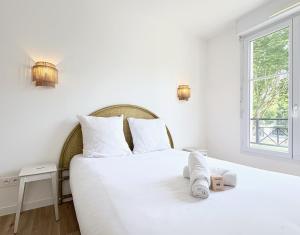 ein Schlafzimmer mit einem weißen Bett mit Handtüchern darauf in der Unterkunft Le Genêt Disney 15min Train 8min Paris Parking in Bussy-Saint-Georges