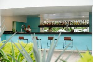 a bar with bar stools and a woman bartender at Fiesta Americana Riviera Nayarit Resort All Inclusive & Spa in Nuevo Vallarta 
