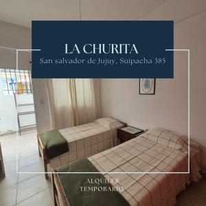 zwei Betten in einem Zimmer mit den Worten la chittoria san salvator de in der Unterkunft La Churita in San Salvador de Jujuy