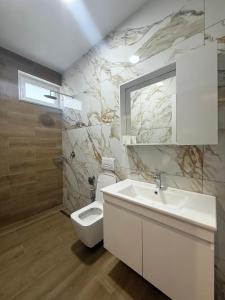 Un baño con un lavabo blanco y un inodoro. en Kalpazo Hotel Tommy Durres, en ((Bishtkamzë ))