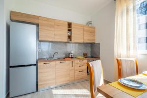a kitchen with wooden cabinets and a white refrigerator at Cozy Lagoon Apartment in Lezhë