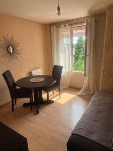 a dining room with a table and chairs and a window at Petit cocon in Château-Chinon