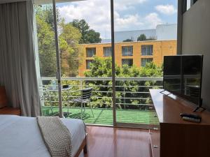 ein Schlafzimmer mit einem Bett und einem großen Fenster in der Unterkunft Lombardo Suites in Mexiko-Stadt