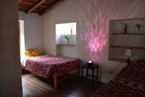 ein Schlafzimmer mit einem Bett und einem Fenster mit einer rosa Wand in der Unterkunft Cabaña rodeada de naturaleza en Ollantaytambo in Ollantaytambo