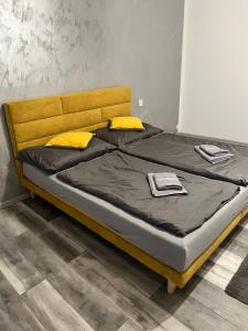 a bed with a wooden head board and yellow pillows at Luxusní apartmán v blízkosti centra města,Wifi, Netxlix in Hradec Králové