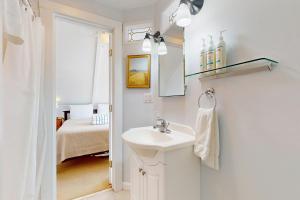 a white bathroom with a sink and a bedroom at Historic Jewel in Provincetown