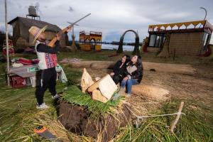 a man with a gun and two women sitting at Titicaca lake views in Puno