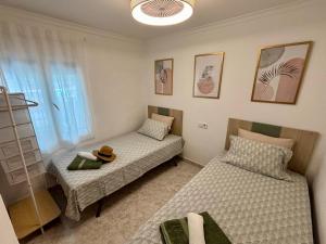 オリーバにあるCASA BAJA OLIVA PLAYAのベッドルーム1室(ベッド2台、テーブルの上に帽子付)