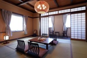 een woonkamer met een tafel, stoelen en ramen bij Matsumoto Hotel Kagetsu in Matsumoto