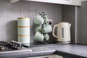 eine Küchentheke mit Tassen und einer Kaffeemaschine in der Unterkunft Three Bedroom House by Brookland Stays Serviced Accommodation Short Lets Wigan with Free WiFi in Hindley