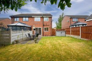 einen Hinterhof eines Backsteinhauses mit einem Zaun in der Unterkunft Three Bedroom House by Brookland Stays Serviced Accommodation Short Lets Wigan with Free WiFi in Hindley