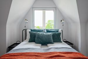 a bedroom with a bed with green pillows and a window at Santorini II - City & Beach by Lion Apartments Sopot in Sopot