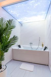 a white bathroom with a tub and a plant at Wellness & Spa Red Paradise in Donje Mladice +17 photos