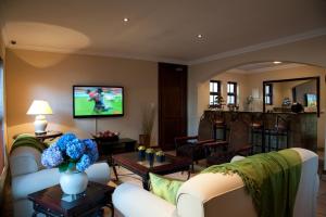 sala de estar con sofá y TV en Rise and Shine Lodge, en Bloemfontein
