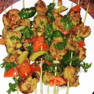a plate of food with shrimp and vegetables on skewers at Spicy Beach Camp in Nuweiba