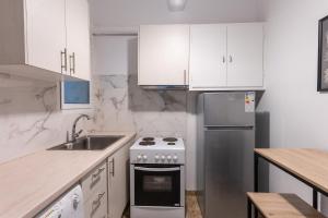 a white kitchen with a stove and a sink at Cozy Nest in Athens +7 photos