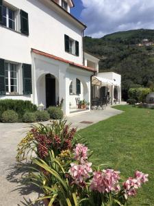een wit huis met roze bloemen in de tuin bij Agriturismo Palmero in Alassio
