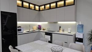 a kitchen with white cabinets and a table with chairs at Aventus Luxury Villa in Rrushkull