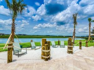 een groep stoelen en palmbomen naast een meer bij Modern Home with Private Pool and Game Room at Storey Lake SL2742 in Kissimmee