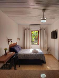 a bedroom with a bed and a table and a window at Explorer Tours Ilha Grande - Apartamentos no Centro da Vila do Abraão in Abraão