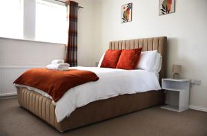 a bedroom with a large bed with red pillows at Home away from Home in Aveley