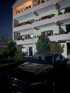 a black car parked in front of a building at Spacious Triple Room with Balcony in Kamëz