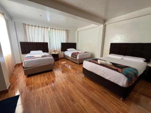 two beds in a room with wooden floors at Tikary Lodge in Cusco +40 photos