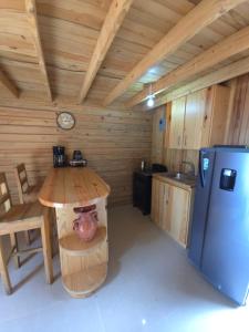 a kitchen with a table and a refrigerator in a cabin at La Casita De La Cueva in Cabo Rojo