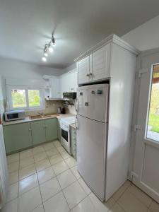 a kitchen with white cabinets and a white refrigerator at Entire villa with big garden and BBQ amenities in Áyios Pávlos