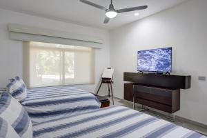 a bedroom with two beds and a tv on the wall at El Tigre, Green Bay I Shared Pool in Nuevo Vallarta  +13 photos