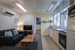 a living room with a couch and a kitchen at Handy Inner City Apartment in Dunedin